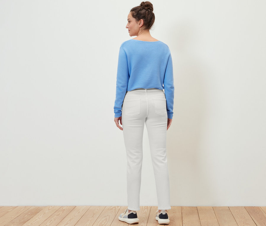 Une femme, vue de dos, porte un jean « Kira », un pull bleu et des baskets.