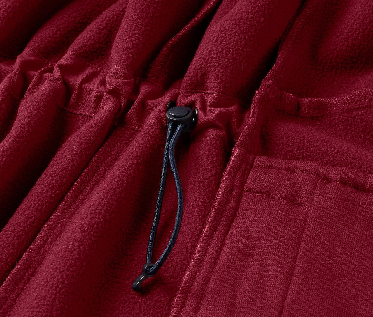Gros plan sur un manteau en softshell rouge foncé avec cordon de serrage.