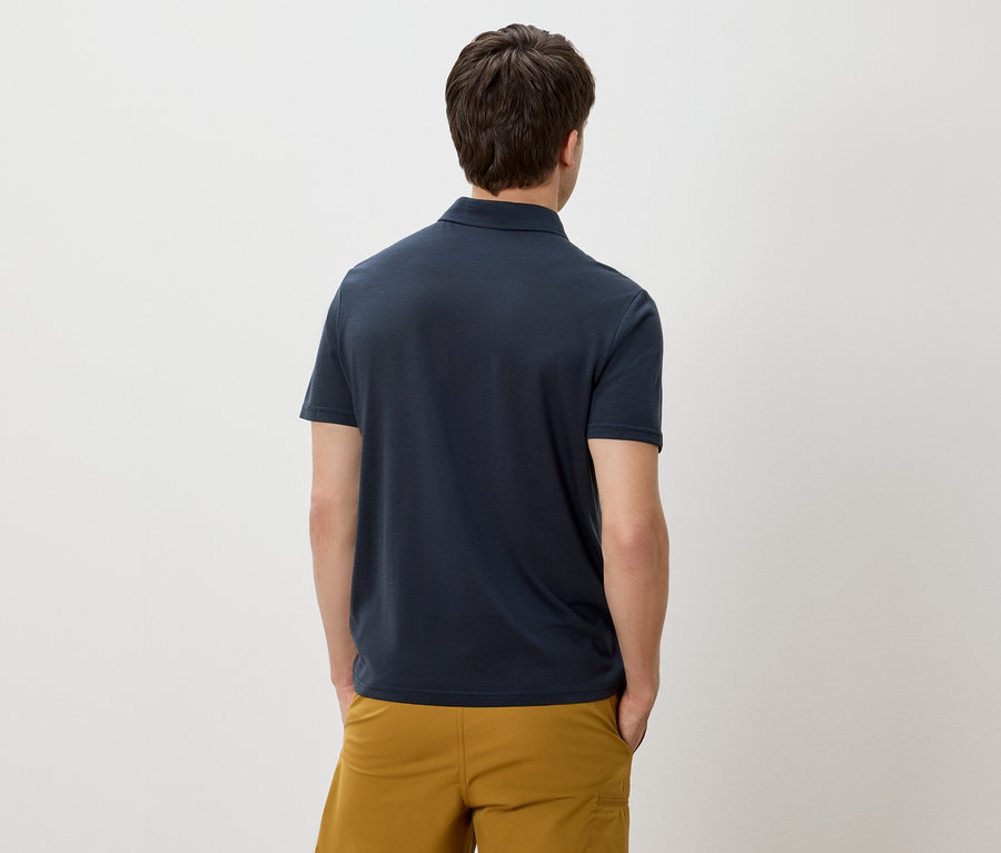 Homme de dos portant un polo bleu marine et un short jaune doré.