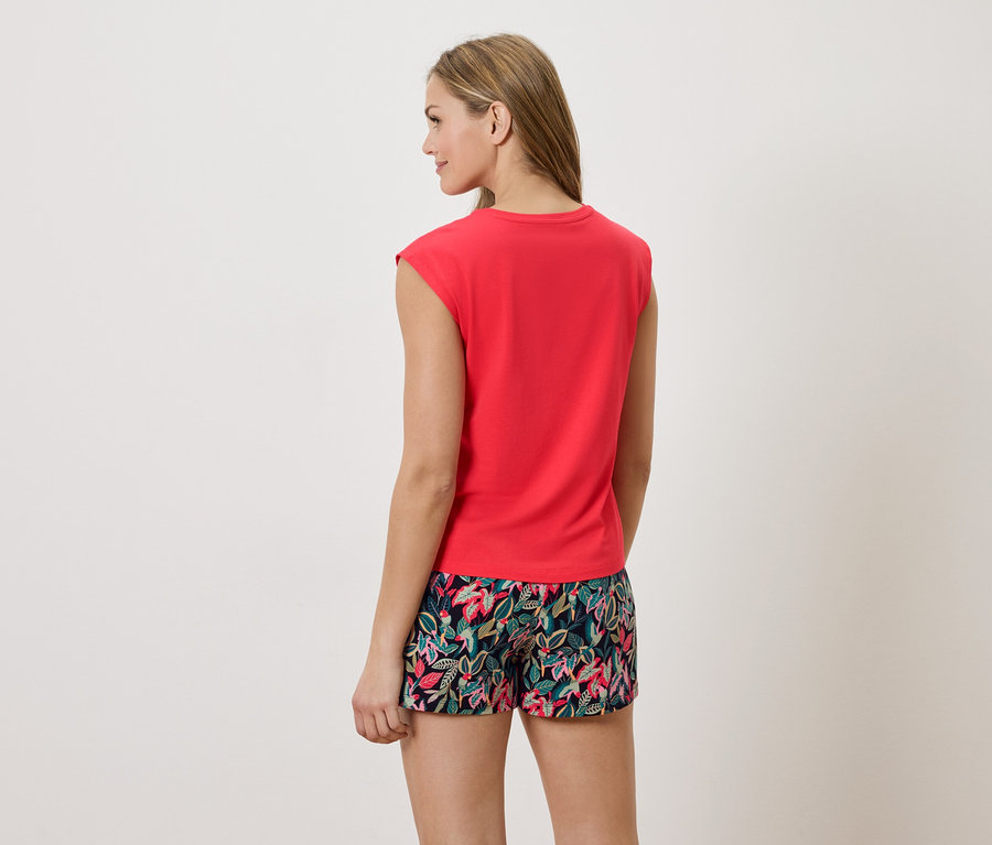Femme de dos portant un t-shirt rouge et un short à imprimé floral.