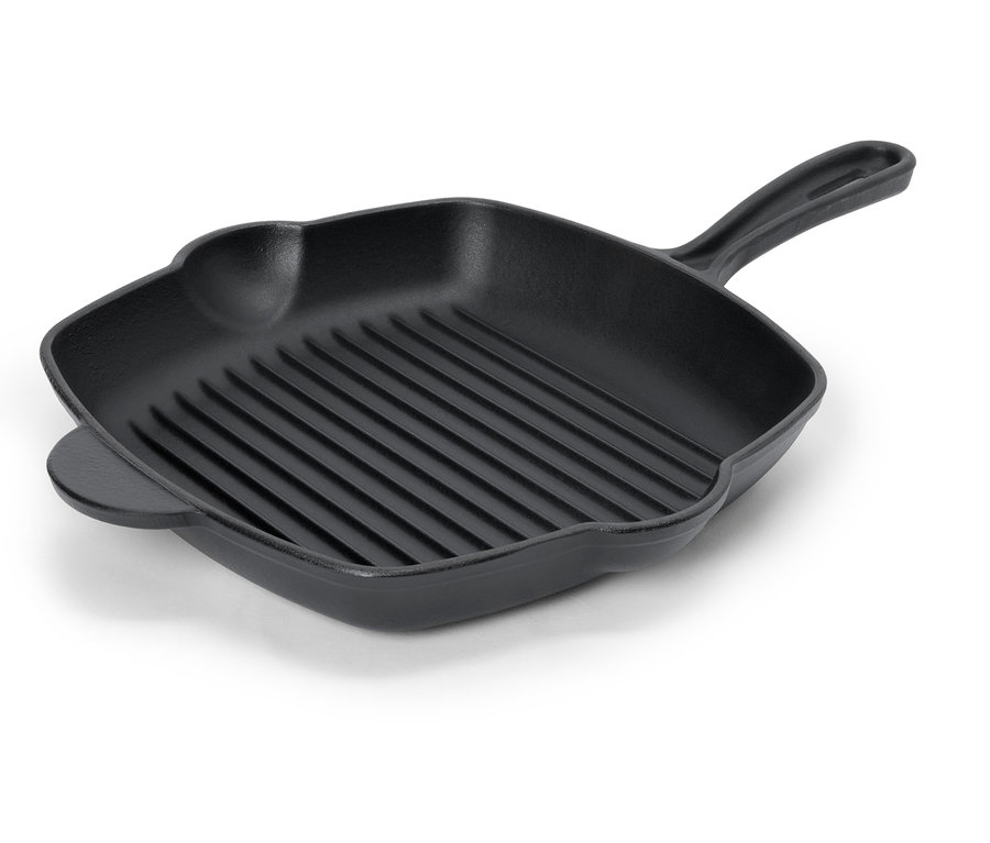 Une poêle à griller noire avec des rainures et une poignée est posée sur une surface blanche.