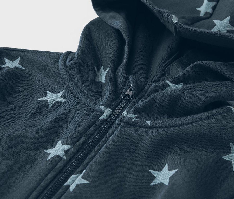 Gros plan sur un sweat à capuche bleu marine à motif étoilé avec fermeture éclair.