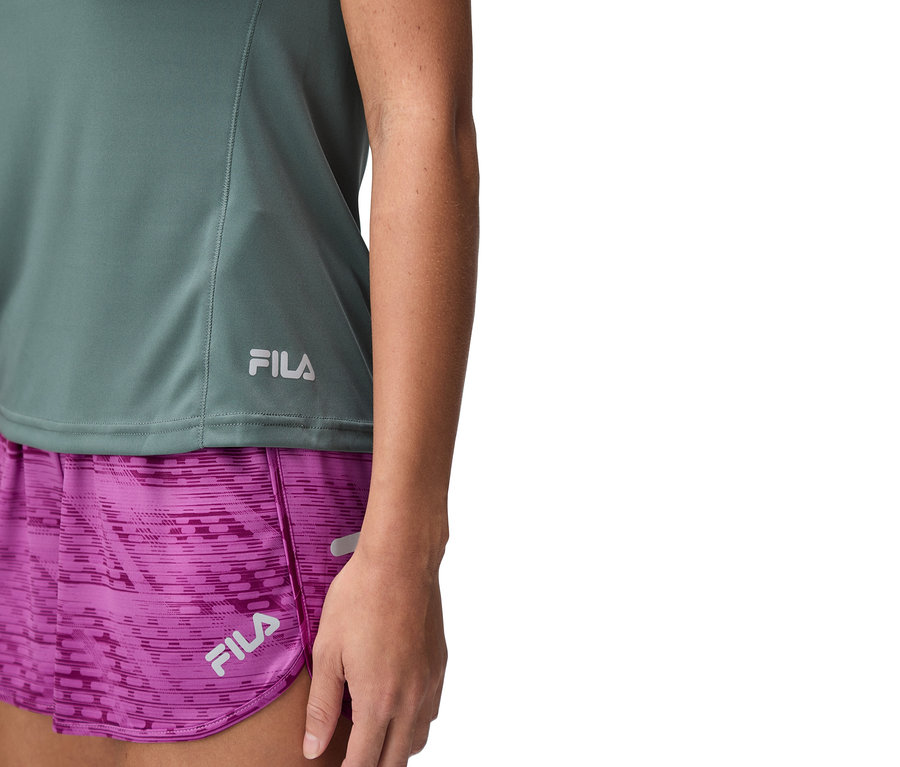Gros plan d'une femme portant un haut Fila vert et un short violet.