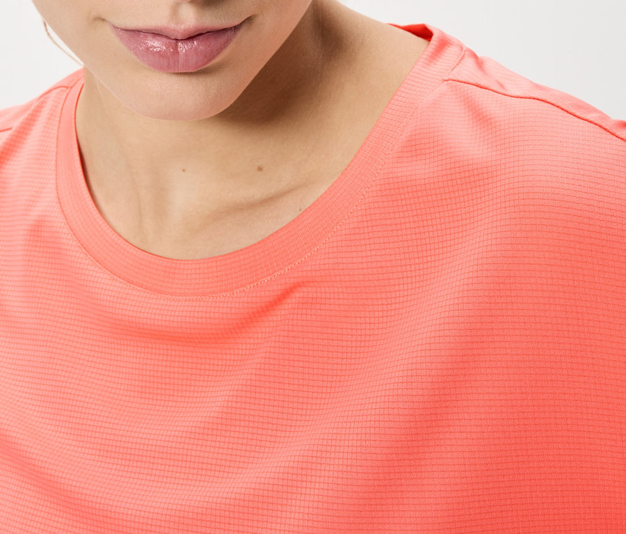 Gros plan d'une femme portant un t-shirt corail.