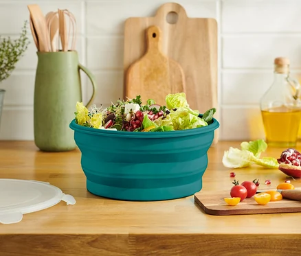 Salade dans un saladier turquoise sur un plan de travail.