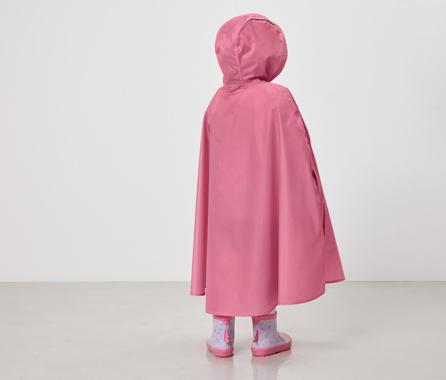 Vue arrière d'un enfant portant un poncho de pluie rose à capuche et des bottes en caoutchouc violettes à motifs sur fond blanc.