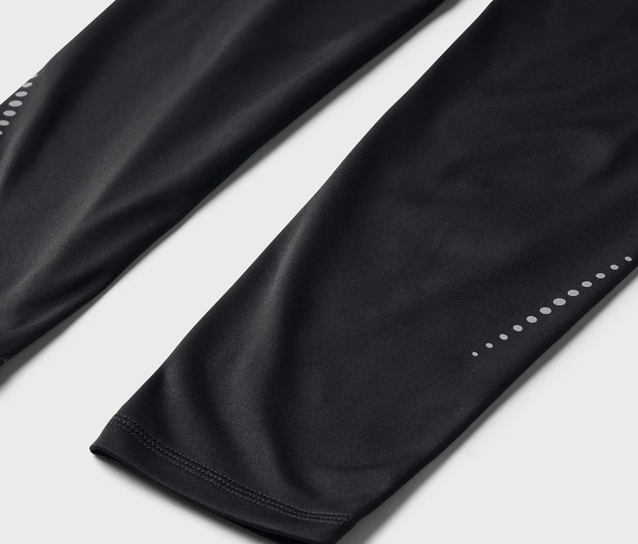 Gros plan sur un legging noir avec des points réfléchissants sur le bas des jambes.