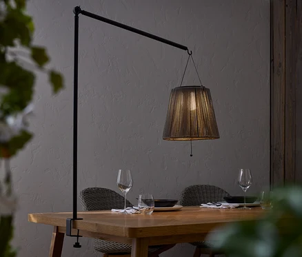 Table à manger avec vaisselle et lampe à abat-jour noir fixée à une barre noire.