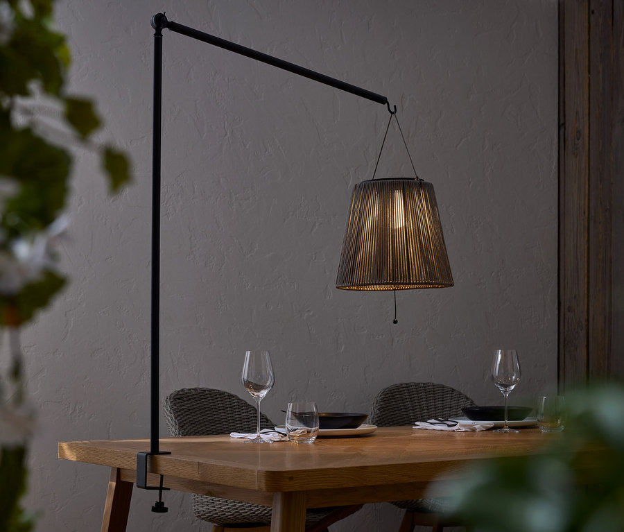 Table à manger avec vaisselle et lampe à abat-jour noir fixée à une barre noire.