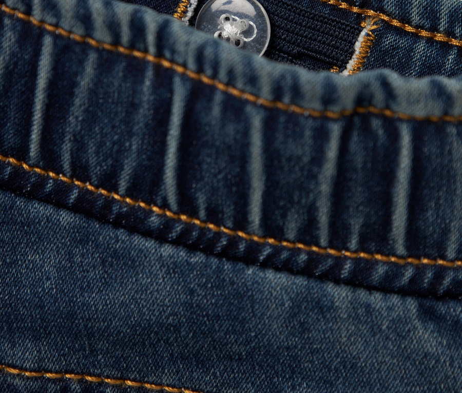Gros plan sur un jean ajustable avec bouton et taille élastique.