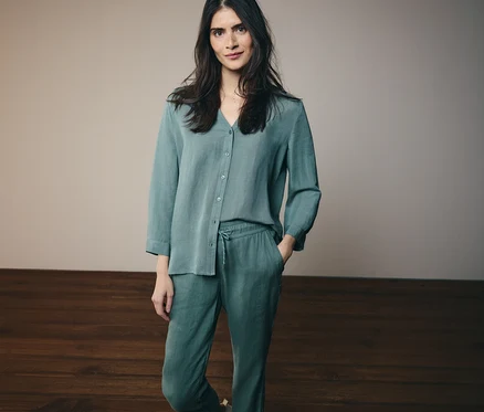 Femme portant une chemise à manches longues et un pantalon assorti vert d'eau avec cordon de serrage, une main dans la poche.