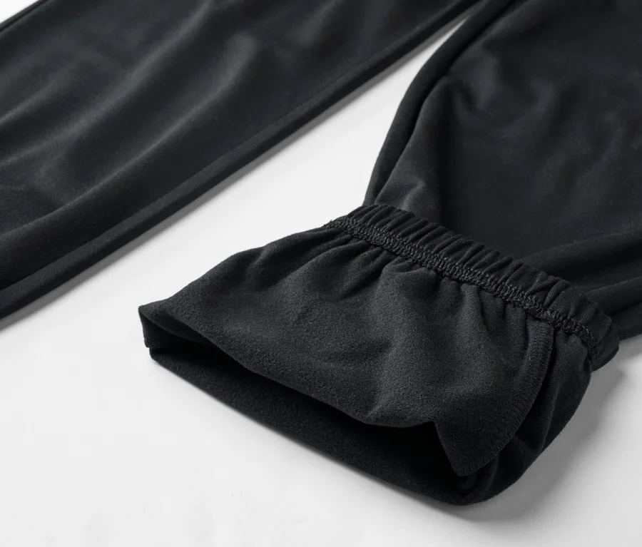 Gros plan d'un pantalon de jogging noir avec élastique à la cheville sur fond blanc.