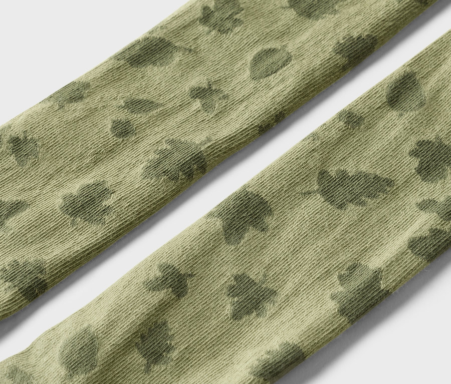 Gros plan de deux bandes de tissu vert olive à motifs sur fond blanc.