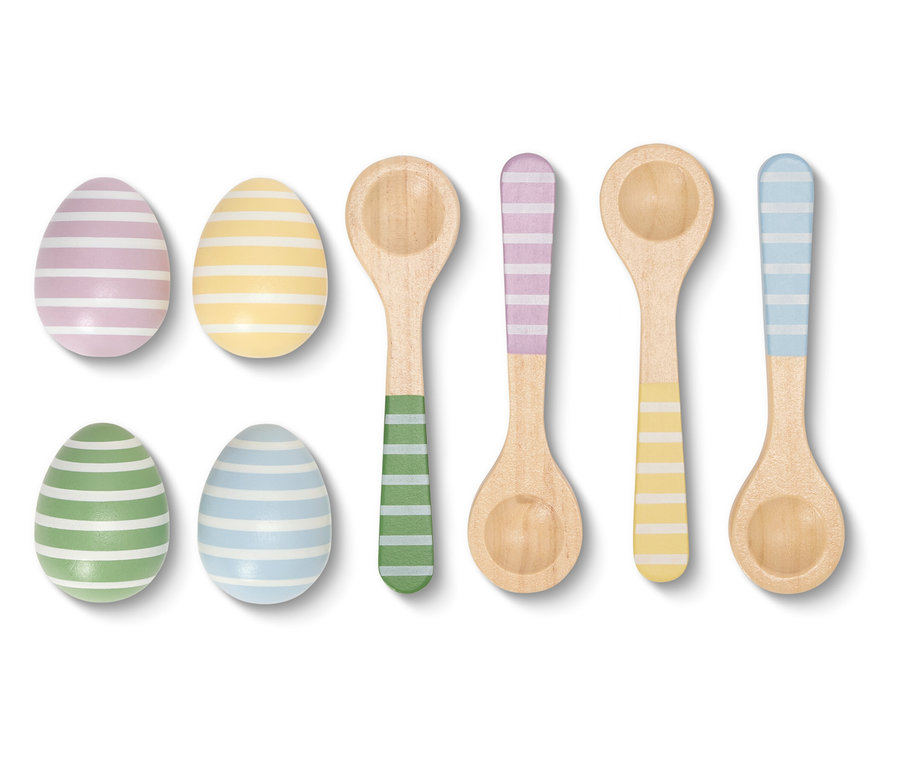 Gros plan sur des œufs de Pâques rayés et des cuillères en bois aux couleurs assorties sur fond blanc.