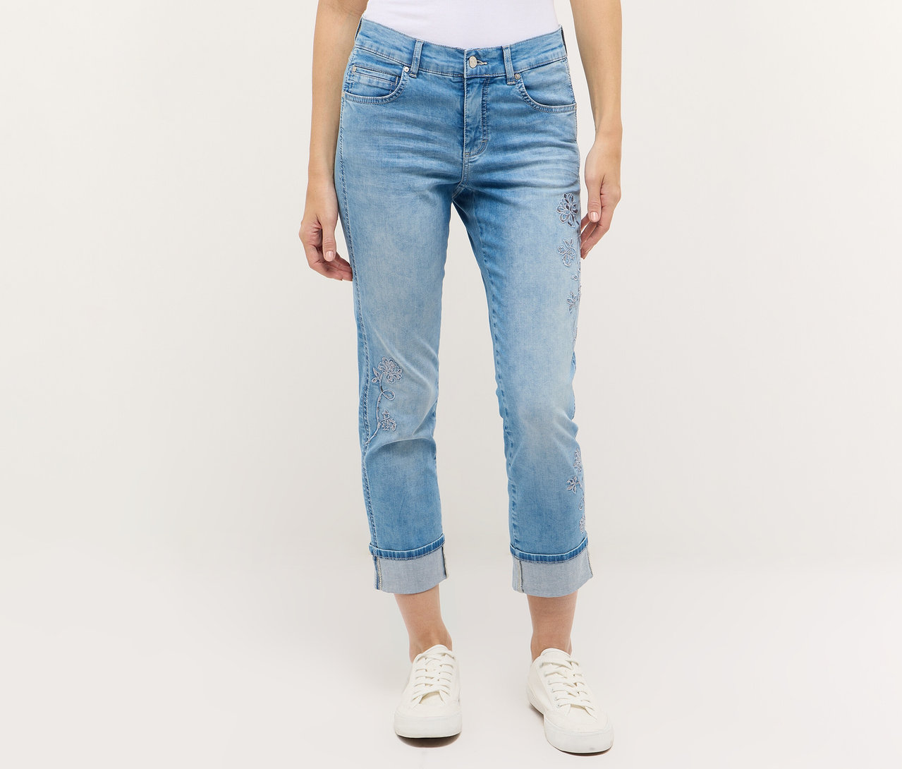 Une personne porte un jean Angels Denim « Cira Boho » et des baskets blanches sur un fond blanc.