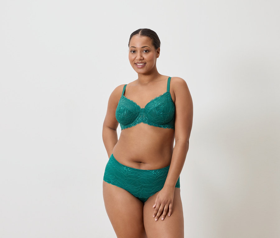 Femme portant un soutien-gorge et une culotte vert émeraude avec un motif en dentelle.