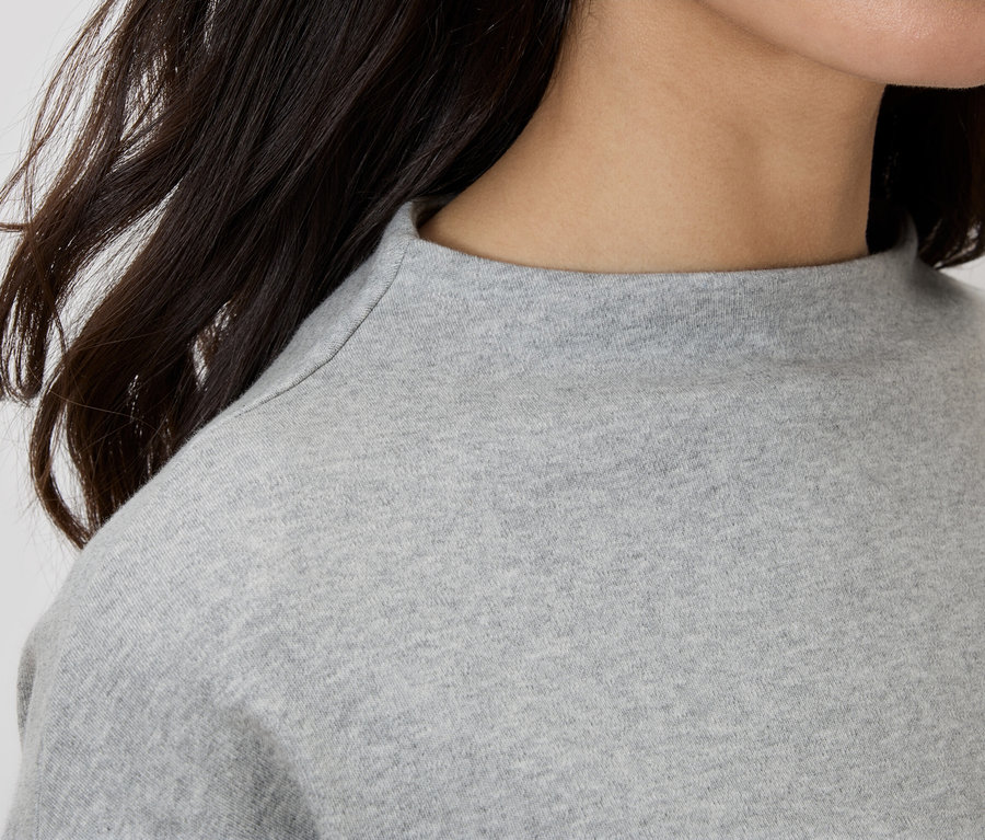 Gros plan d'une femme portant un haut gris à col roulé.