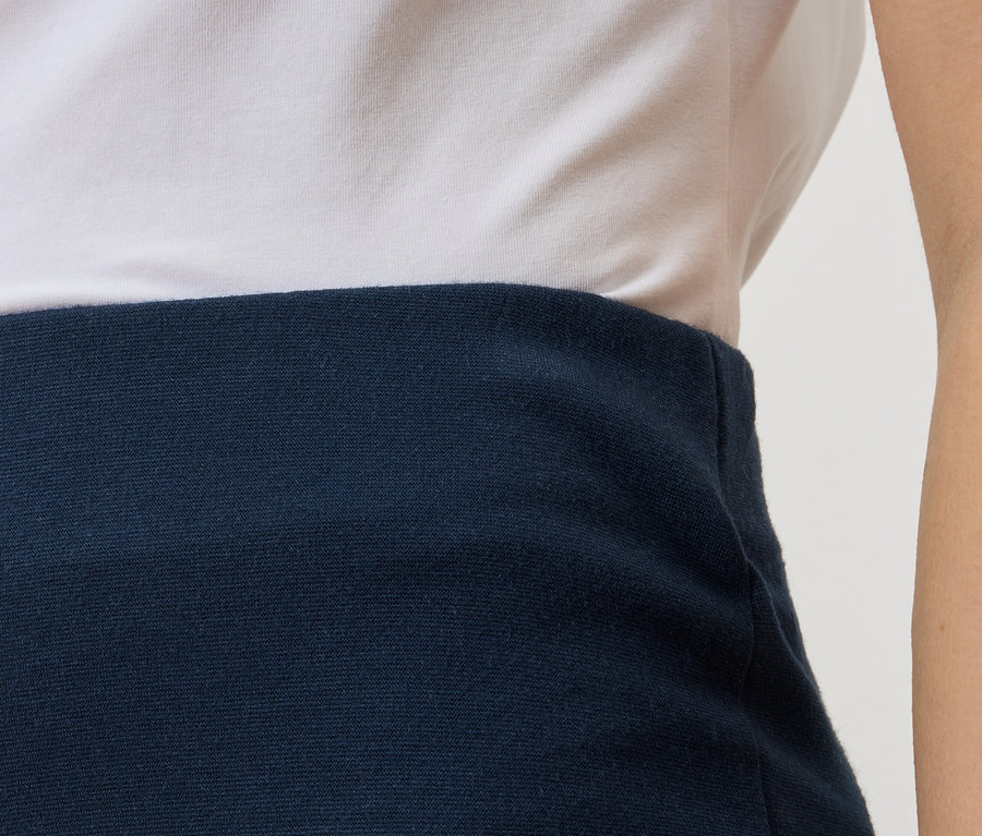 Gros plan sur une partie du haut du corps d'une personne portant un t-shirt blanc et une jupe bleu marine.