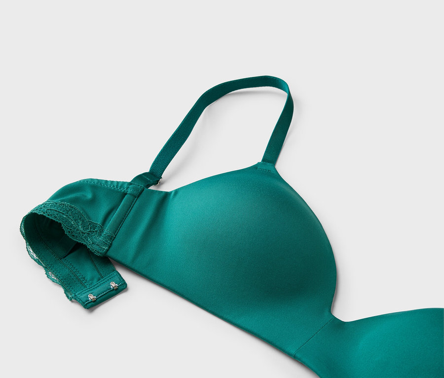 Gros plan d'un soutien-gorge vert avec de la dentelle et des bretelles réglables sur un fond gris clair.