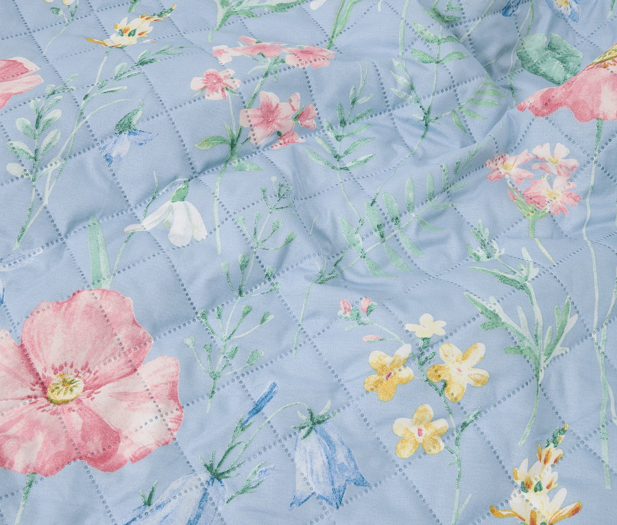 Gros plan d'une courtepointe bleu clair avec un motif floral.