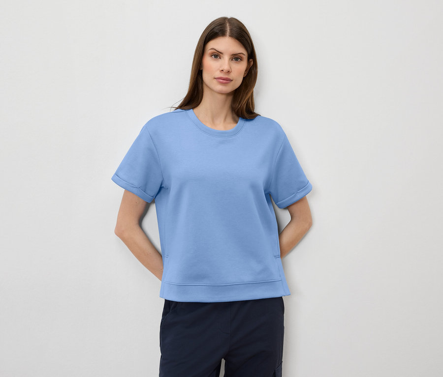 Femme portant un t-shirt bleu clair et un short bleu marine.