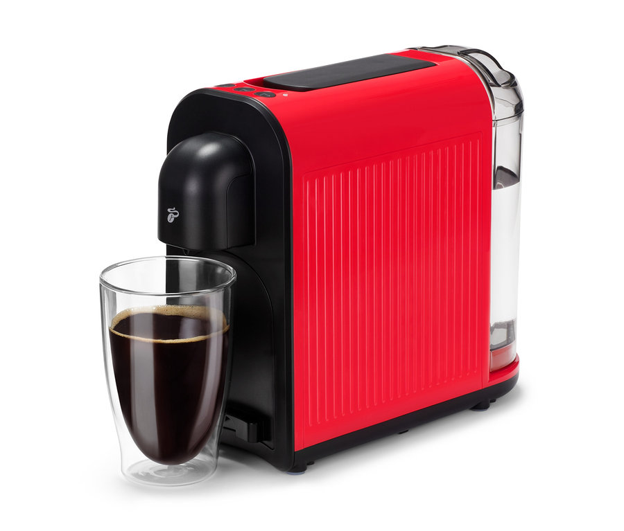 Une machine à café rouge Cafissimo now red est à côté d'un verre de café noir.