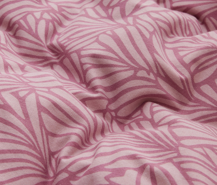 Tissu rose avec un motif de feuilles rose foncé, drapé en plis doux.
