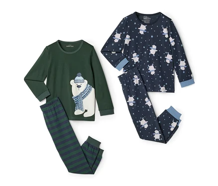Deux ensembles de pyjamas pour enfants sont posés à plat sur un fond blanc. À gauche, un ensemble vert foncé avec un grand motif d'ours polaire sur le haut et un pantalon rayé. À droite, un ensemble bleu foncé avec un motif intégral de petits ours polaires et d'étoiles.