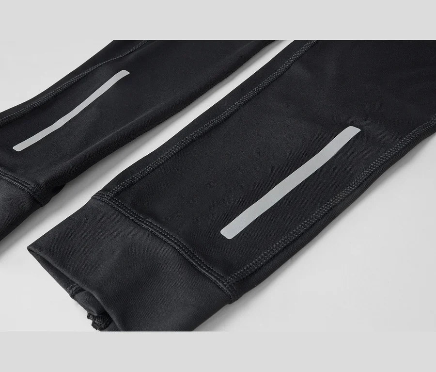 Gros plan de deux manches ou jambes de pantalon noires avec des bandes réfléchissantes et des coutures visibles.