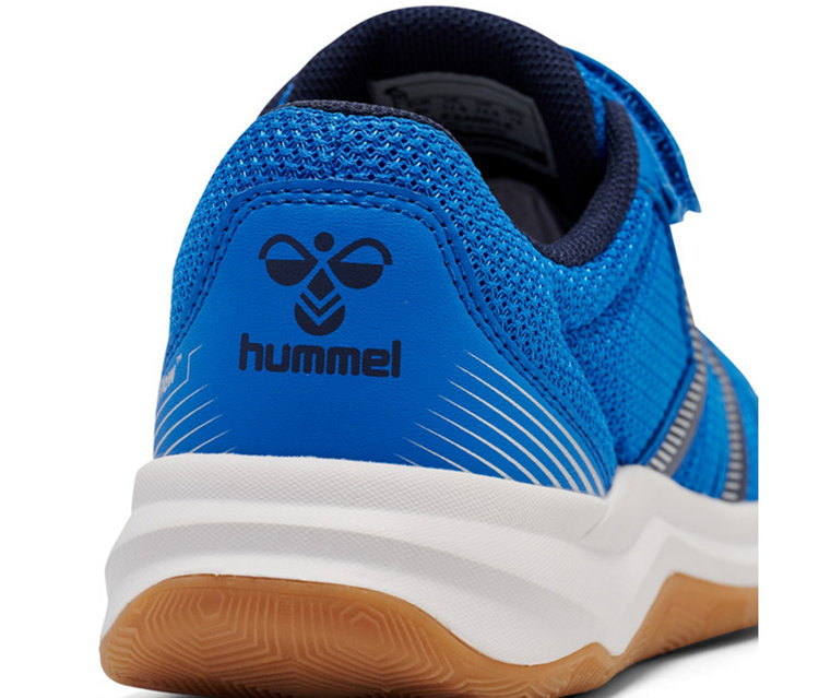 Gros plan du talon d'une chaussure de sport bleue avec le logo Hummel, une semelle intermédiaire blanche et une semelle extérieure en gomme marron.