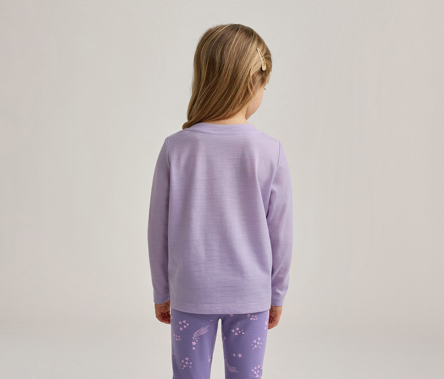 Fille vue de dos, portant un haut lavande à manches longues et un pantalon lavande assorti avec des motifs d'étoiles blanches. Ses cheveux blonds sont attachés avec une pince.