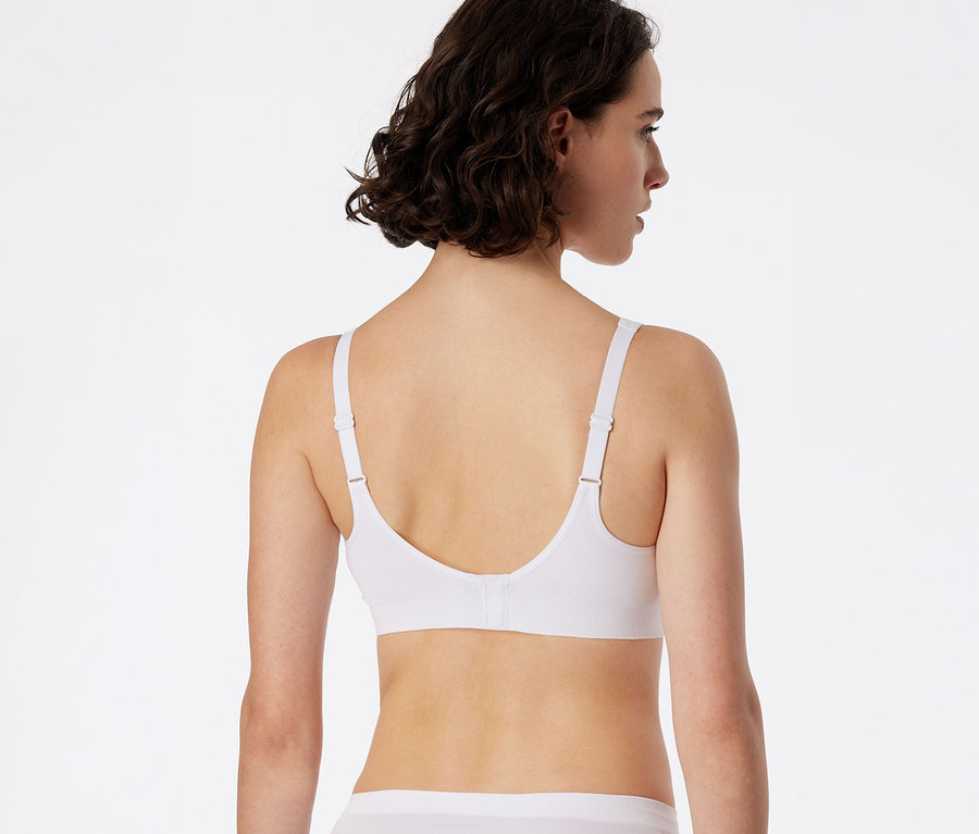 Femme vue de dos, légèrement tournée vers la droite, portant une brassière douce SCHIESSER blanche avec coussinets et un slip blanc.