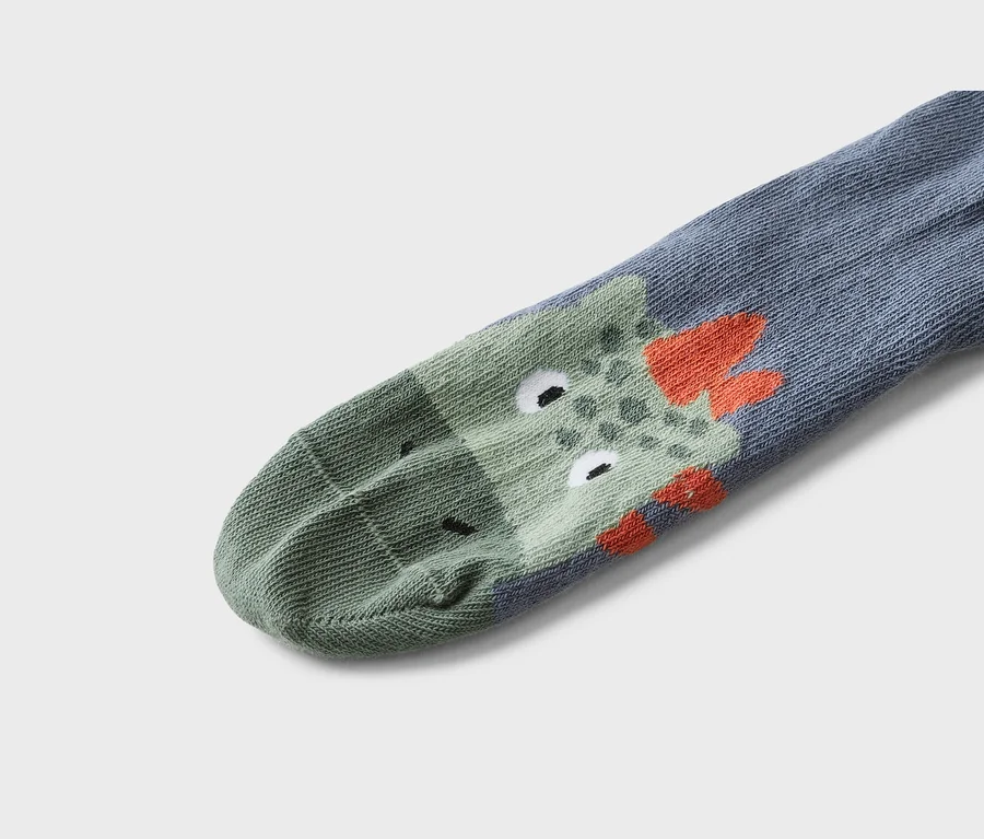 Gros plan d'une chaussette grise avec un motif de crocodile vert et des détails orange.