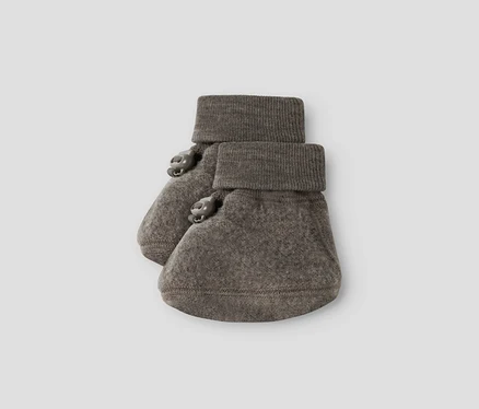 Une paire de chaussons de bébé gris-brun avec des poignets côtelés et deux petits boutons décoratifs sur le côté de chaque chausson.