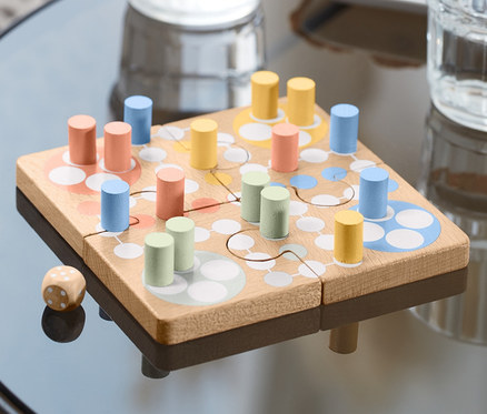Sur une table se trouve un Puzzle Ludo avec des pions colorés et un dé.