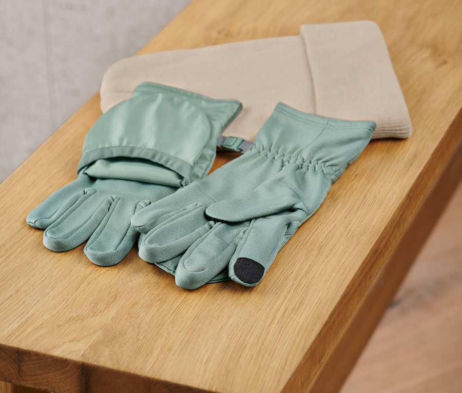 Une paire de gants de course à pied avec rabats posés sur un banc en bois.