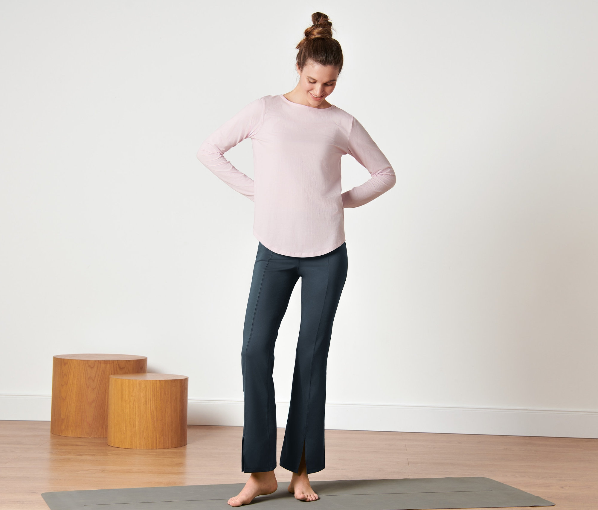 Femme debout sur un tapis de yoga portant un pantalon de sport modelant bleu foncé.