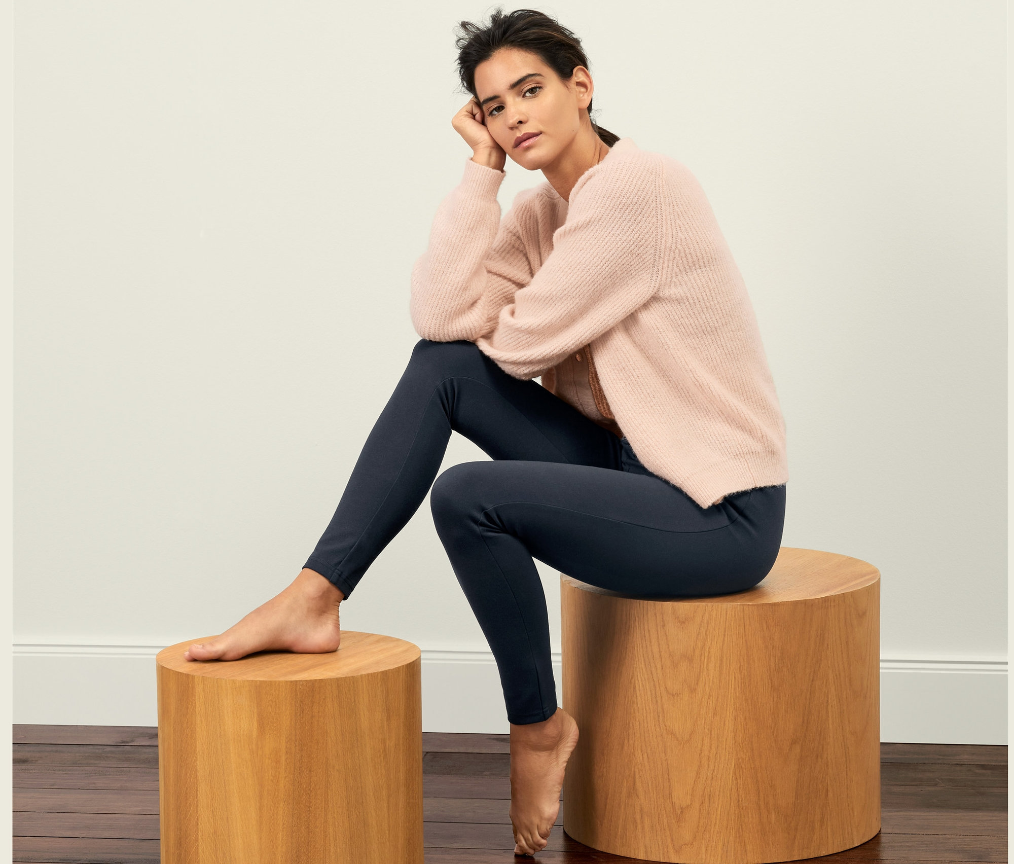Femme assise sur un tabouret en bois portant un legging en jersey lourd.