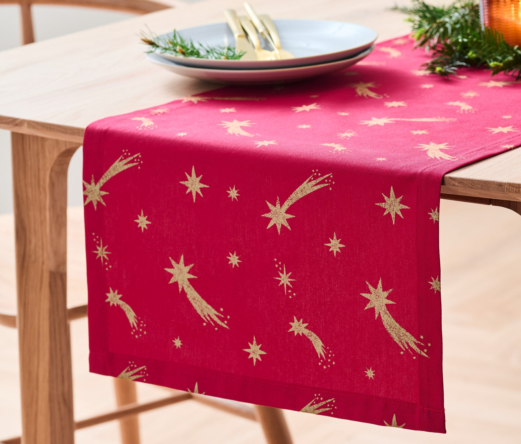 Sur une table en bois se trouve un chemin de table en coton avec un imprimé étoiles.