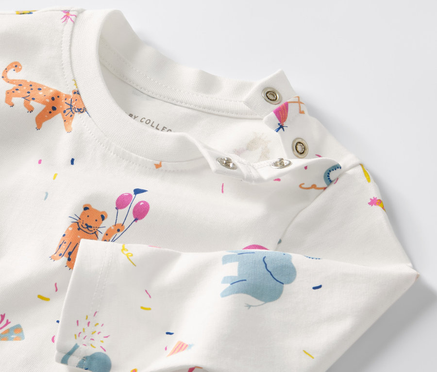 Gros plan sur un haut à manches longues pour bébé avec motif d'animaux et de confettis.