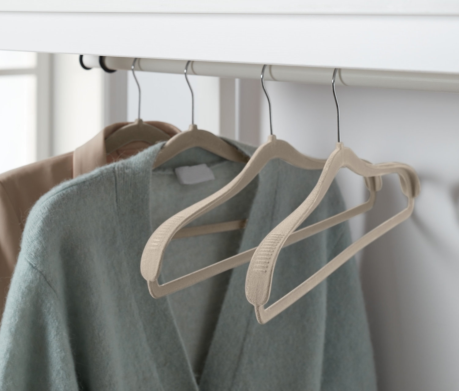 Deux vestes suspendues sur 4 cintres avec renfort aux épaules sur un cadre blanc.