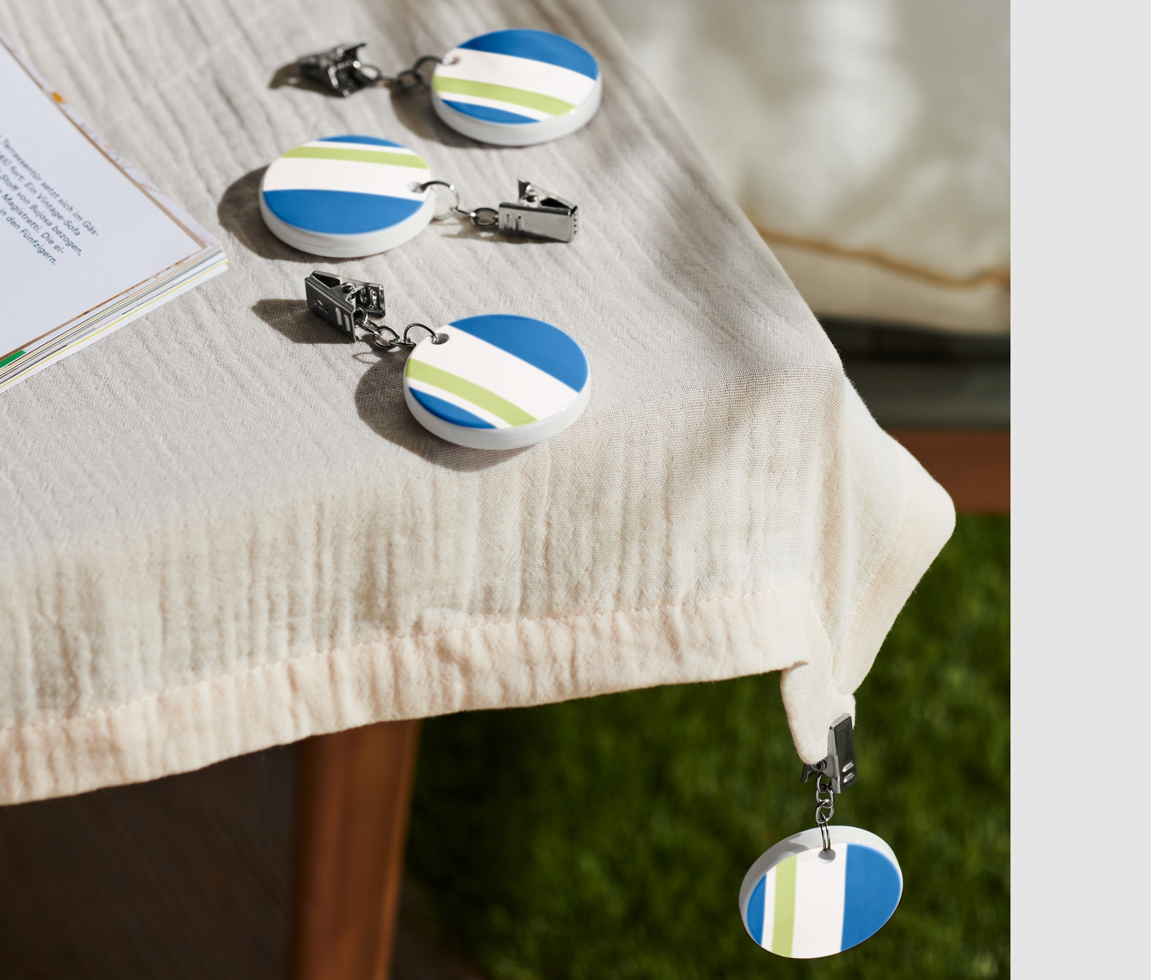 Sur une table, quatre pinces à nappe sont posées à côté d'une tasse de café et d'un livre.