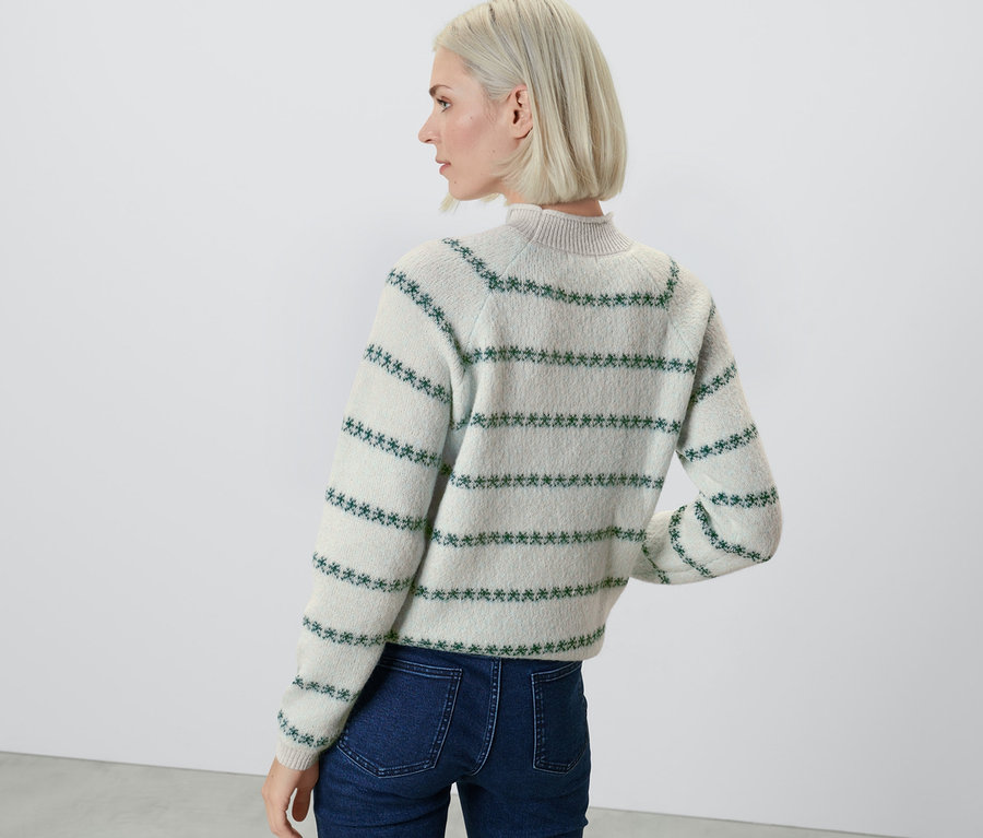 Une femme, vue de dos, porte un pull en maille à motifs bleus.