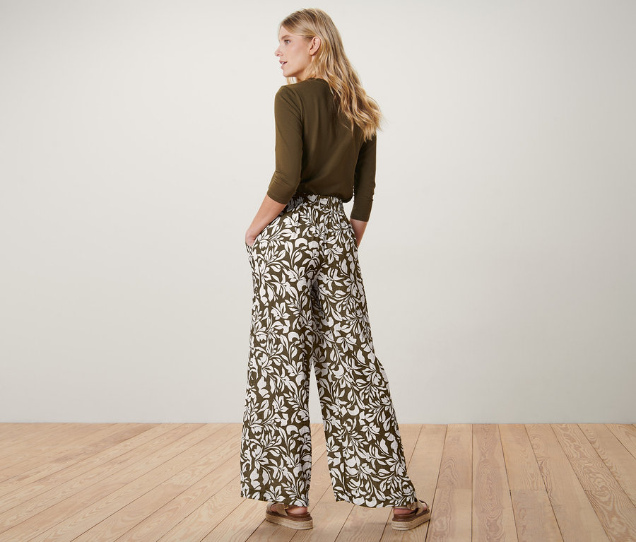 Une femme, vue de dos, a les mains dans les poches de son pantalon imprimé à taille élastique.