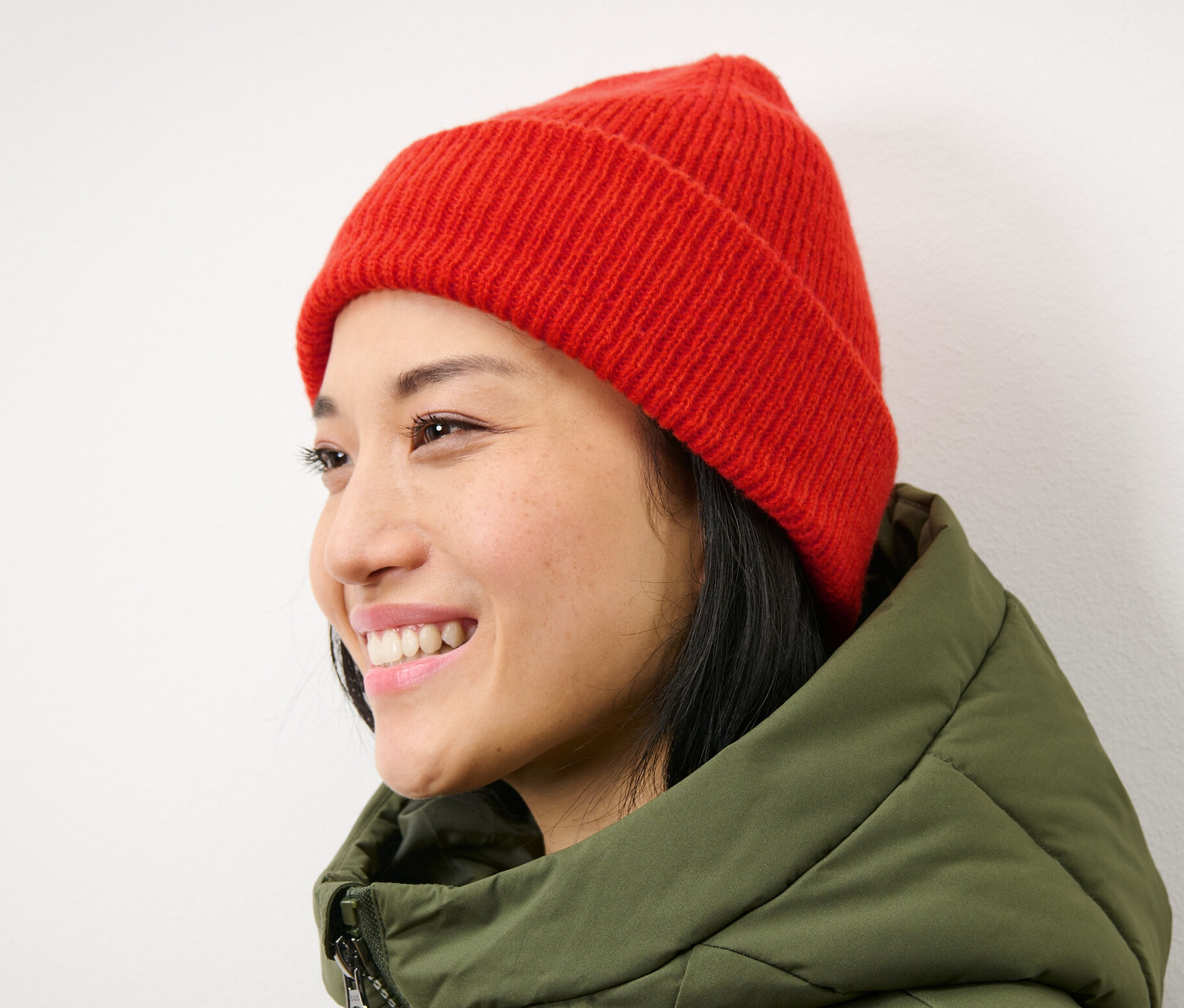 Femme souriante portant un bonnet en maille orange.