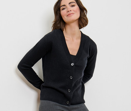 Femme posant en cardigan en maille fine avec du cachemire et pantalon gris.