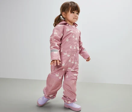 Fillette portant une combinaison de pluie pour enfant, cygne. Elle porte des bottes en caoutchouc violettes.