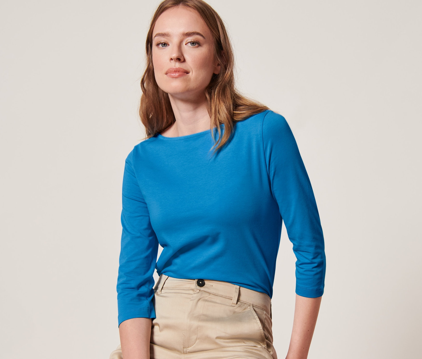 Femme assise sur un tabouret portant un t-shirt manches 3/4 bleu azur.