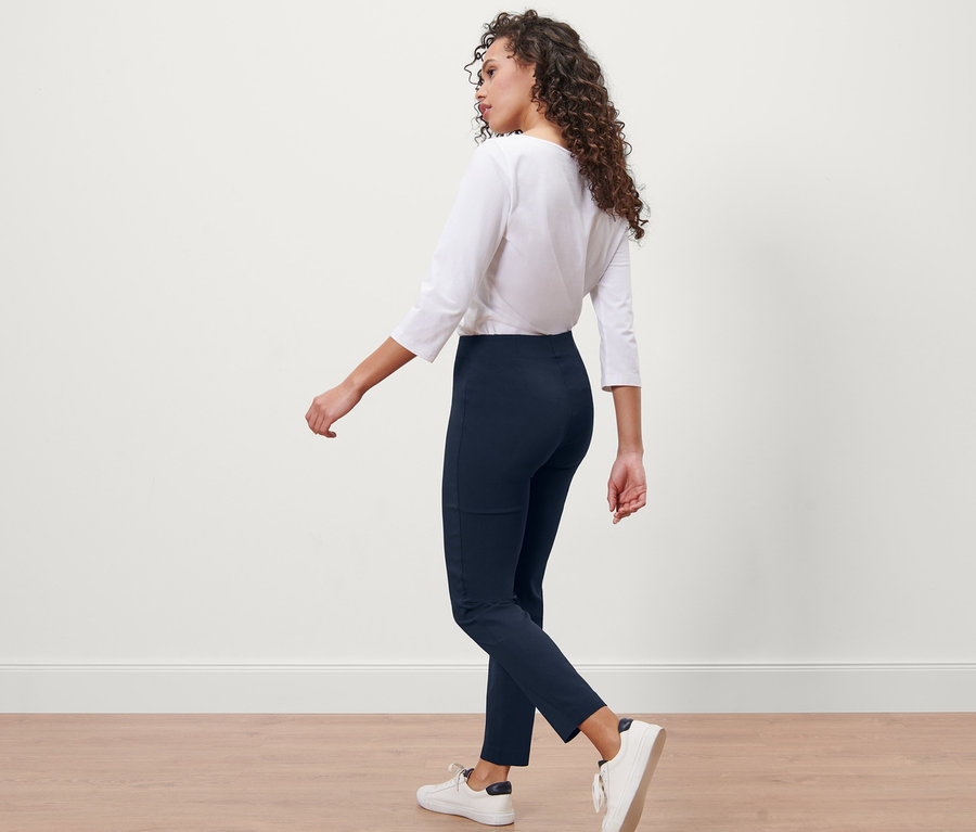 Femme marchant et portant un pantalon stretch bleu foncé.