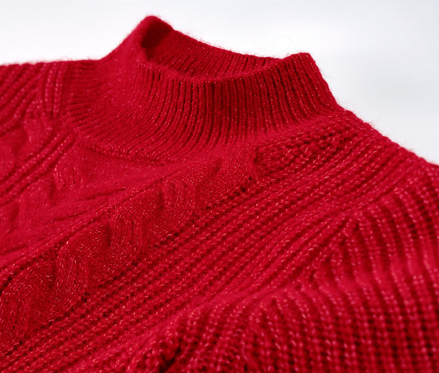 Gros plan sur un pull rouge en grosse maille à motif torsadé.